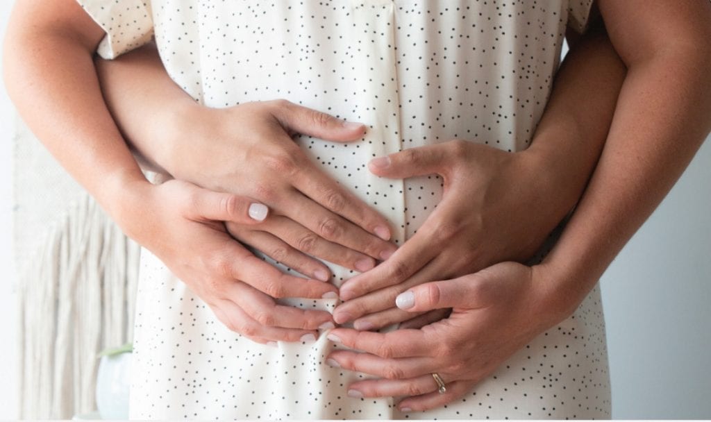 couple holding hands over baby bump